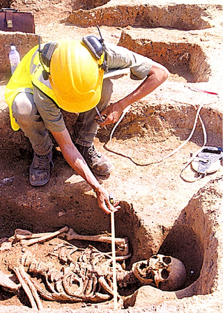 An archaeologist examines the intact remains of a spooky "skeleton person."